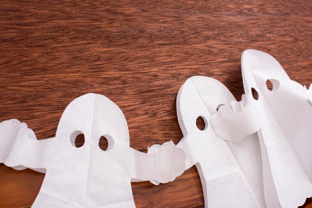 halloween ghost paper decorations on a wood background