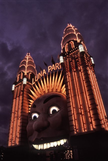 gate to theme park with a face at dusk with stromy sky