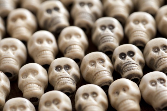 Hallowee  background of multiple white toy plastic skulls packed closely together viewed low angle with shallow dof