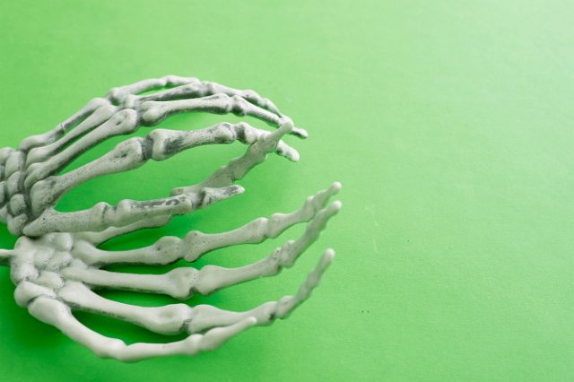 halloween concept of boney skeleton fingers hands on a green background