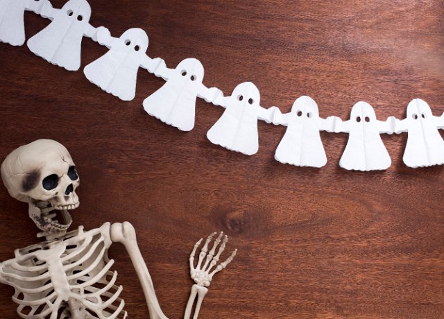 a halloween backdrop featuring a chain of paper ghosts and a waving skeleton character