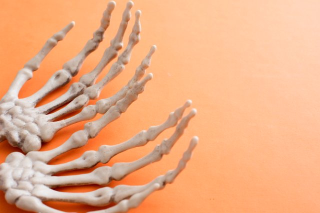 halloween background of skeleton hands on orange with space for text