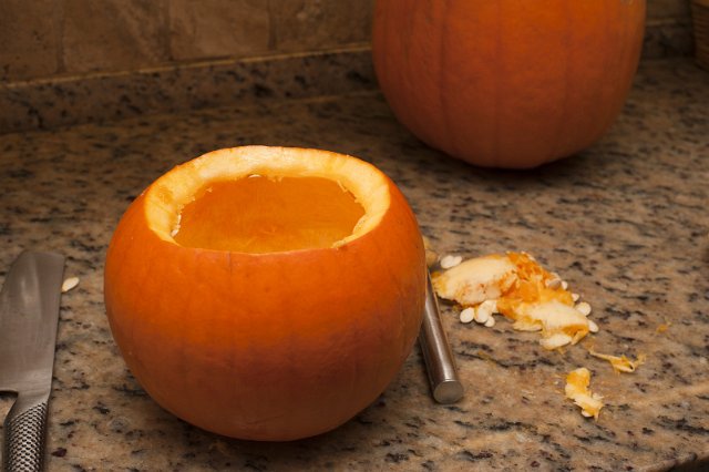 Preparing a Halloween jack-o-lantern by first hollowing out the pulp of the pumpkin with a kitchen knife