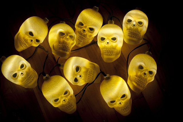 Top down view on nine plastic skulls lit from within over wooden background for concept about halloween or death