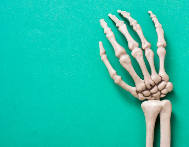 a spooky halloween skeleton hand on a green background with space for text