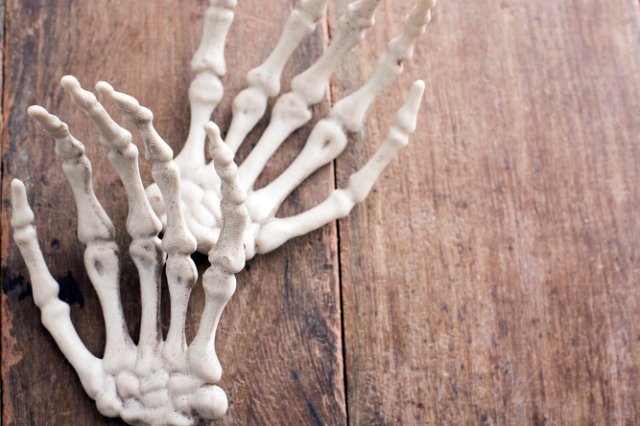 halloween concept of skeleton hands on a wooden backdrop