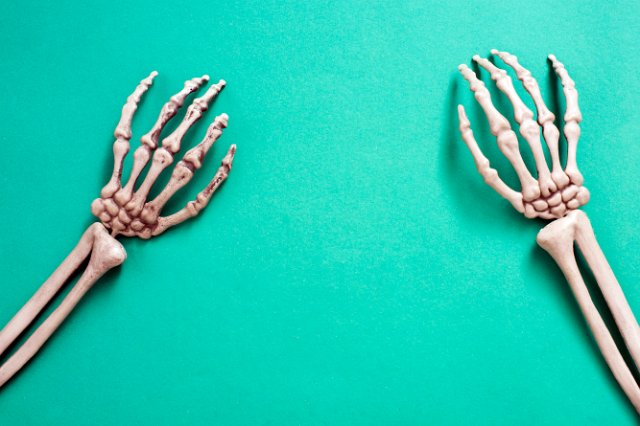 creepy skeleton arms and hands on a green backdrop with space for a haloween message